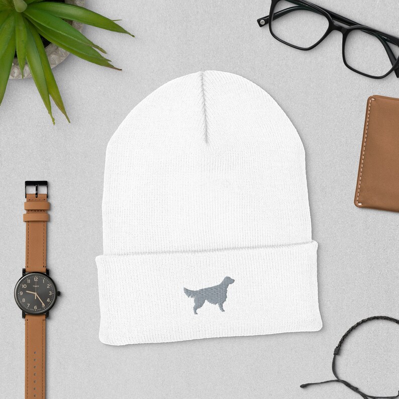 May include: White knit beanie with a gray embroidered silhouette of a golden retriever.