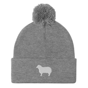 May include: Gray knit beanie with a white sheep silhouette embroidered on the front and a gray pom pom on top.