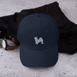 May include: A navy blue baseball cap with a white embroidered silhouette of a dog on the front.