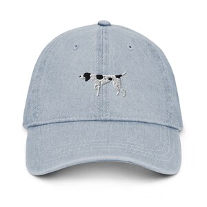 May include: A light blue denim baseball cap with an embroidered black and white dog on the front.
