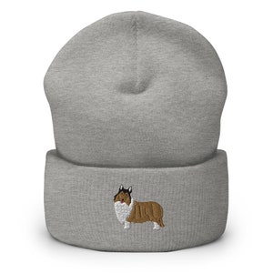 May include: A gray knit beanie with a brown and white embroidered Collie dog on the front.