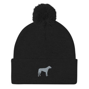 May include: Black knit beanie with a fluffy pom pom on top and a gray embroidered silhouette of a dog on the front.