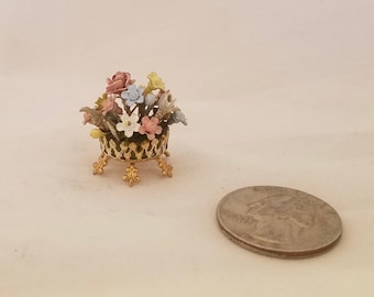 Tabletop floral arrangement in brass-colored container.