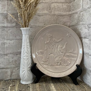 May include: A white ceramic plate with a raised design of the three wise men following a star. The plate is on a black stand and says "Lo-The Wise Men Rejoice-32".