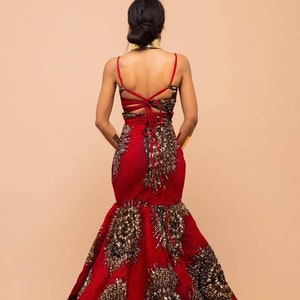 May include: A red and gold mermaid-style gown with a low back and a lace-up detail. The gown is adorned with gold sequins and beads.