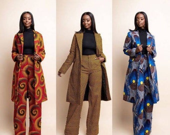 May include: Three women wearing matching patterned suits with long coats. The suits feature vibrant colors and unique designs. Each woman wears a black turtleneck. The suits are in red, yellow, blue, and brown.