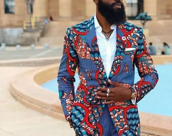 May include: A man wearing a blue, red, and white patterned suit jacket and matching pants. He is wearing a white shirt, sunglasses, and a silver necklace.