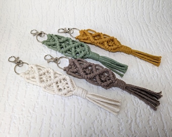May include: Four macrame keychains with tassels in white, green, brown, and yellow.