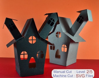 May include: Two black paper Halloween houses with cut-out windows and doors. The houses are stacked on top of each other. The text "Manual Cut: Level 2/5 Machine Cut: SVG Files" is printed below the houses.