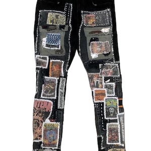 May include: Black denim jeans with various patches sewn on. The patches feature band logos, images, and text, including "Harley-Davidson", "Pantera", and "Steez D.I.Y."
