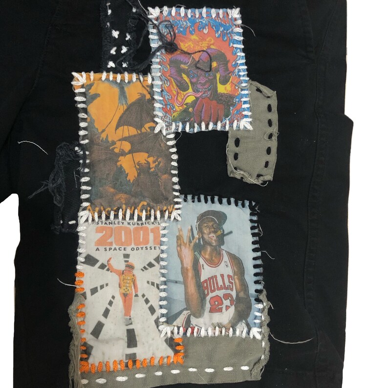 Puede incluir: Prenda negra con parches cosidos que presentan im&aacute;genes de la pel&iacute;cula "2001: Una odisea del espacio", un jugador de baloncesto y otros gr&aacute;ficos. Los parches est&aacute;n cosidos con hilo blanco y naranja, creando un dise&ntilde;o art&iacute;stico &uacute;nico.