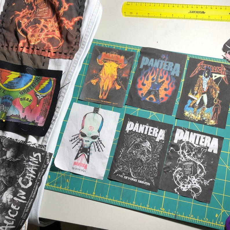 Puede incluir: Un conjunto de parches de bandas de m&uacute;sica, incluyendo Pantera, Metallica y Alice in Chains, con fondos negros y varios dise&ntilde;os gr&aacute;ficos. Algunos parches est&aacute;n sobre tela blanca. Tambi&eacute;n se ve una regla amarilla. Los parches est&aacute;n sobre una esterilla de corte verde.