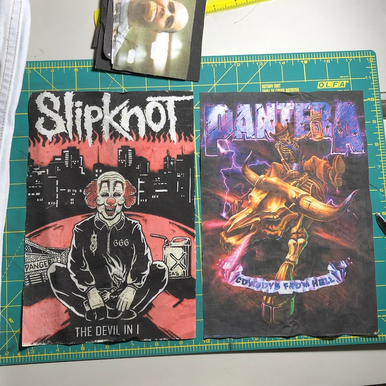 Puede incluir: Dos parches de tela negra con logotipos de bandas. Un parche muestra "Slipknot" sobre una ilustraci&oacute;n de payaso con el texto "THE DEVIL IN I". El otro parche muestra "PANTERA" con un esqueleto montando un toro y el texto "COWBOYS FROM HELL".