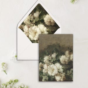 May include: A white envelope with a floral design on the inside flap. The design features white flowers with green leaves on a brown background.