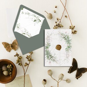 Op de afbeelding: Een huwelijksuitnodiging met een aquarelbloemendesign in tinten groen en roze. De uitnodiging is gedrukt op wit papier en heeft een waszegel met een gouden afwerking. De uitnodiging wordt getoond op een wit oppervlak met eucalyptus takken en vlinders.