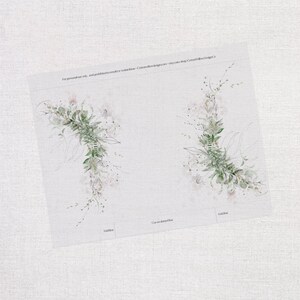 Op de afbeelding: Twee aquarel illustraties van groene, bladerige bloemkransen met delicate roze accenten. De kransen bevinden zich op een witte achtergrond met de tekst "Knip op de gestippelde lijn" en "Vouwlijn" eronder.