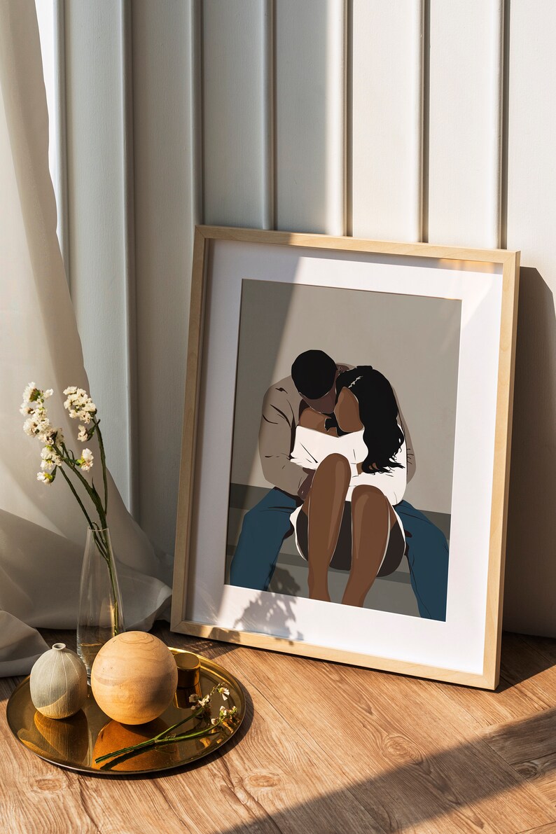 May include: A framed illustration of a couple embracing. The man is wearing a brown jacket and blue jeans. The woman is wearing a white top and has long black hair. The background is a light gray color.