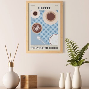 May include: A framed print featuring coffee cups and the word "COFFEE" in a minimalist design. The print includes the text "WE LOVE COFFEE" at the bottom. The background is a light blue checkered pattern.