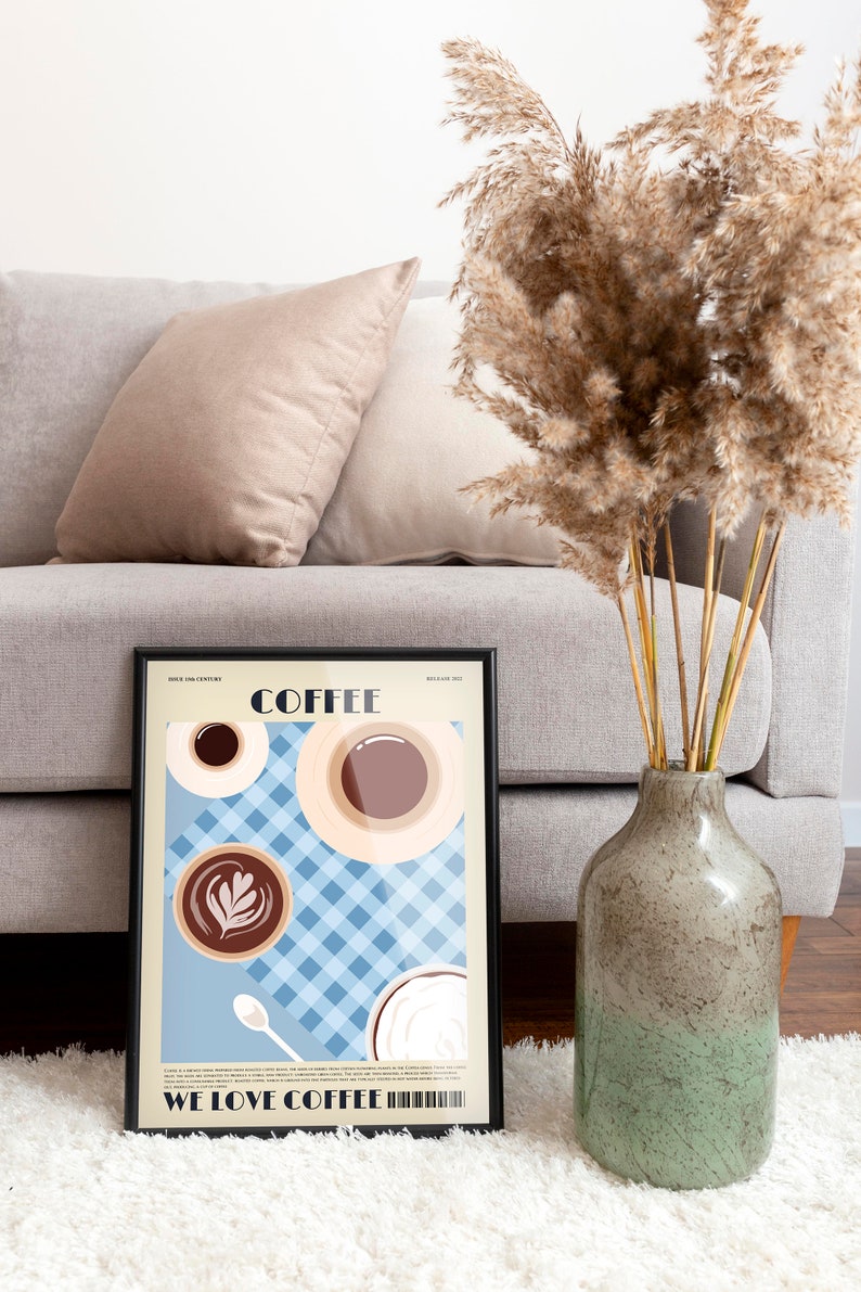 May include: A framed coffee-themed art print with a black border, featuring coffee cups and the text "COFFEE" and "WE LOVE COFFEE". The print is displayed on a white rug, with a gray sofa and decorative vase in the background.