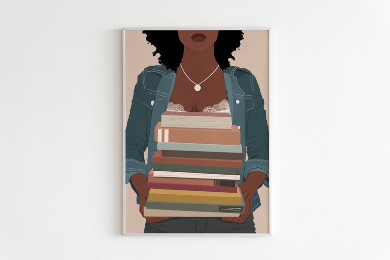 May include: A woman with curly black hair is wearing a blue denim jacket and holding a stack of books in front of her chest. The books are various colors and sizes.
