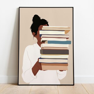 Peut inclure: Impression artistique d'une personne tenant une pile de livres. La personne porte une chemise blanche et a les cheveux noirs en chignon. Les livres sont de couleurs vari&eacute;es, dont le bleu, le marron et le beige. L'&oelig;uvre est encadr&eacute;e.