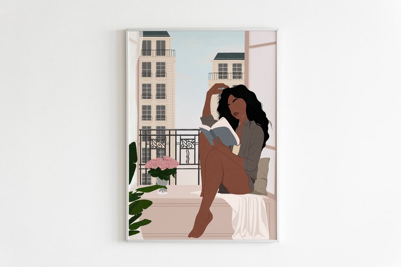 May include: A woman with long, dark hair sits on a balcony reading a book. She is wearing a gray shirt and has a white blanket draped over her legs. There are buildings in the background and a potted plant with pink flowers on the balcony.