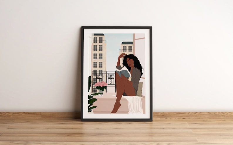 May include: A framed illustration of a woman sitting on a balcony reading a book. The woman has long dark hair and is wearing a gray shirt. The balcony has a view of a city with buildings in the background. There are pink flowers in a pot on the balcony.