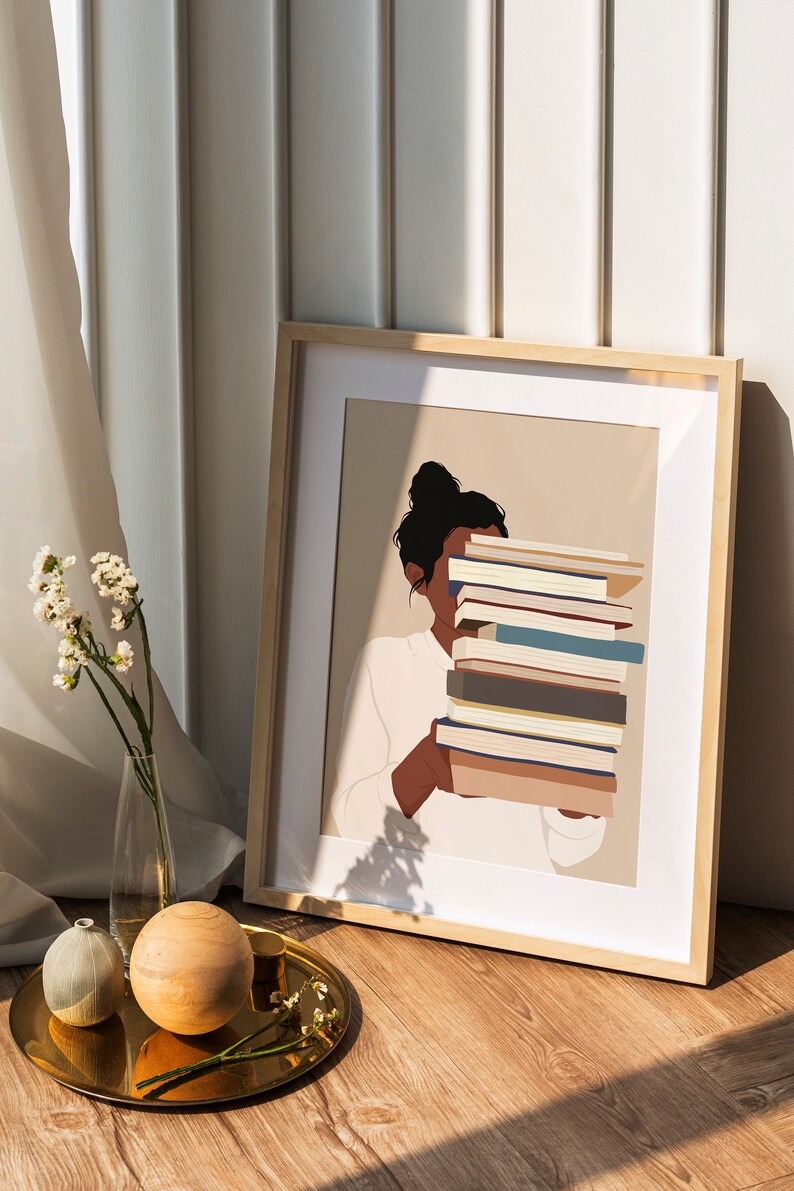 Peut inclure: Impression d'art encadr&eacute;e repr&eacute;sentant une personne tenant une pile de livres. L'illustration est minimaliste, avec une palette de couleurs neutres et un cadre en bois clair. L'image est pos&eacute;e sur un fond neutre.