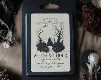 May include: A black rectangular package containing soy wax melts. The label reads "Witching Hour" with a spooky tree and house illustration. The net weight is 3 oz / 85 grams. The product is handcrafted in MI.