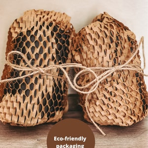 May include: Two items wrapped in brown paper honeycomb packaging tied with twine. The text "Eco-friendly packaging" is written in a brown circle.