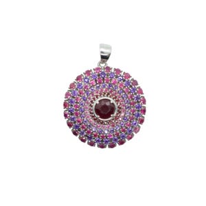 May include: A silver pendant with a round, multi-colored gemstone design. The pendant features a large, red gemstone in the center surrounded by smaller pink and purple gemstones.