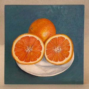 May include: A painting of three oranges on a white plate. The oranges are cut in half, revealing their juicy, red flesh. The plate is on a teal background.