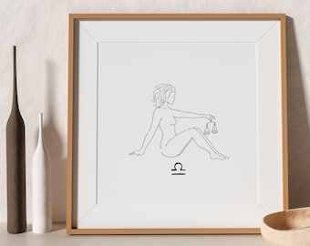 May include: A framed print of a line drawing of a woman sitting with a scale, representing the zodiac sign Libra. The frame is brown wood and the print is on white paper.