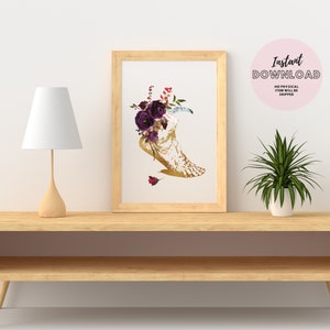 Pu&ograve; includere: Un download digitale stampabile di una luna crescente dorata con fiori viola e piume. L'immagine &egrave; incorniciata ed esposta su uno scaffale con una lampada e una pianta in vaso.