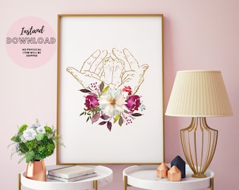 May include: A printable digital art print featuring a gold outline of two hands holding a baby's footprints with a floral arrangement of burgundy, white, and green flowers.