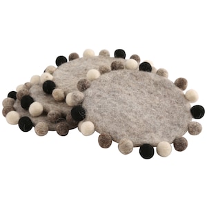 May include: Set of three round felt coasters with a decorative pom-pom trim. The coasters are gray with black and white pom-poms.