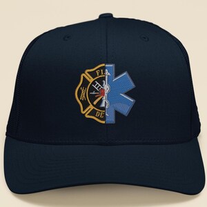 May include: A navy blue trucker hat with a split design featuring a gold firefighter emblem on the left side and a blue star of life emblem on the right side.