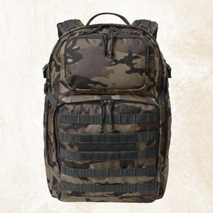 May include: A camouflage-patterned backpack in shades of brown, green, and black. The backpack features multiple compartments, including a front pocket and a main compartment with a zipper closure. It has adjustable shoulder straps and a top handle for carrying.