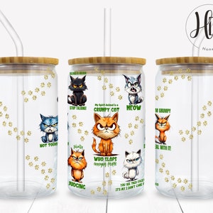 May include: Two clear glass tumblers with bamboo lids and straws. The tumblers have a white background with gold paw prints and cartoon cats with humorous sayings. The sayings include "My Spirit Animal is a Grumpy Cat", "Stop Talking!" and "Not Today".
