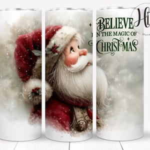 May include: A white tumbler featuring a festive Santa Claus design. Santa is depicted in a red suit and hat with a long white beard, set against a snowy background. The text "BELIEVE IN THE MAGIC OF CHRISTMAS" is also displayed.