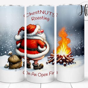 May include: A white tumbler with a Christmas scene featuring Santa Claus, a bag of gifts, and a campfire with the text "Chestnuts Roasting On An Open Fire".