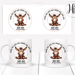 Pode incluir: Caneca de cerâmica branca com uma ilustração de desenho animado de um burro marrom. O burro está sorrindo e tem o texto "DUMB-ASS, KISS-ASS, SMART-ASS, JACK-ASS" ao redor. O texto "BAD-ASS" está abaixo do burro e o texto "It's your choice" está abaixo disso.