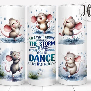 May include: A white tumbler with a quote about learning to dance in the rain. The quote is surrounded by illustrations of cute cartoon mice dancing in the rain.