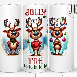 May include: A white tumbler with a cartoon reindeer wearing a red sweater and a green wreath around its neck. The reindeer has Christmas lights and ornaments hanging from its antlers. The text "Jolly as Fah la la la la la" is printed on the tumbler.