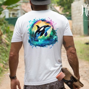 May include: White t-shirt with a watercolor design of an orca jumping out of the water. The orca is black and white with a blue and green watercolor background.