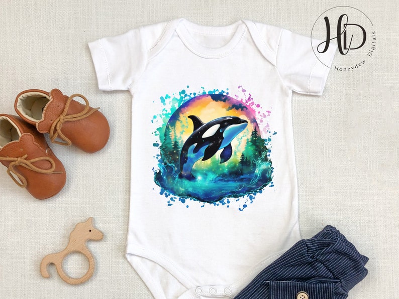 May include: White baby onesie with a watercolor design of an orca whale jumping out of the water. The design features a colorful background with splashes of blue, green, and purple.