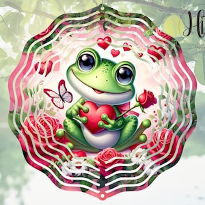 May include: A pink and white metal wind spinner with a green frog holding a red heart. The frog is surrounded by red roses and white flowers. The wind spinner has a layered design with multiple circles.