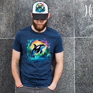May include: A navy blue t-shirt with a watercolor design of an orca jumping out of the water. The orca is surrounded by a colorful splash of water and a sunset. The t-shirt has a white and black trucker hat with a small orca design on the front.