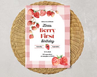 Puede incluir: Una invitación a cuadros rosas y blancos con fresas en acuarela. El texto dice "Linas Berry First Birthday" con detalles de fecha y hora. La invitación está sobre un mantel individual redondo tejido.