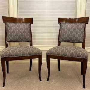 May include: Two brown wooden dining chairs with a patterned fabric seat and back.